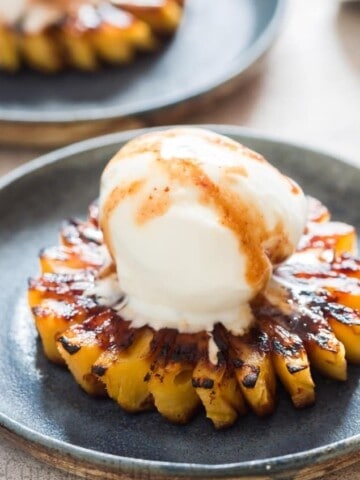 Grilled pineapple with rum brown sugar glaze topping with a scoop of vanilla ice cream