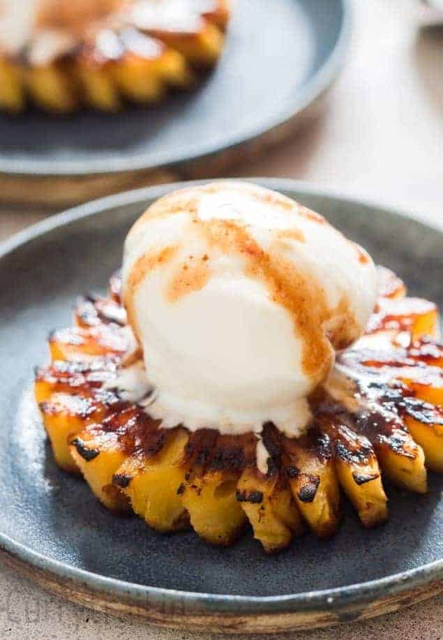 Grilled pineapple with rum brown sugar glaze topping with a scoop of vanilla ice cream