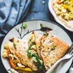 2 Folded whole wheat crepes with scrambled eggs and bell peppers on a plate