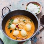Egg stew in a cast iron pan with rice hoppers on the side
