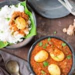 spicy south Indian egg curry served in black clay plate with rice on side
