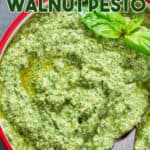 fresh basil walnut pesto in bowl with wooden spoon with text overlay