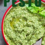 walnut basil pesto in small bowl with wooden spoon with text