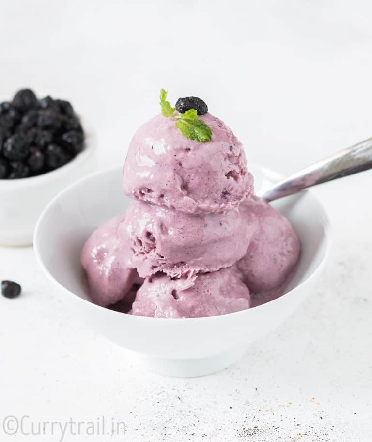 blueberry frozen yogurt in white bowl with a spoon