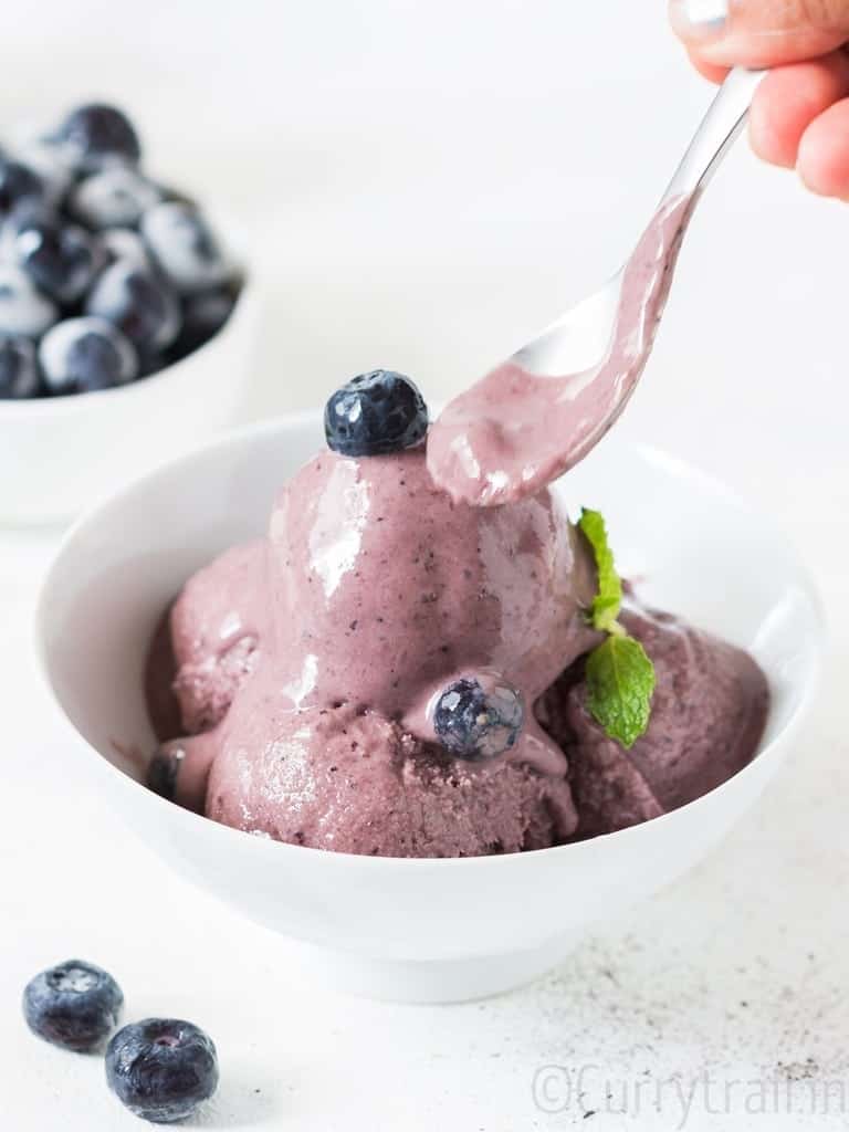 blueberry frozen yogurt in white bowl with a spoon