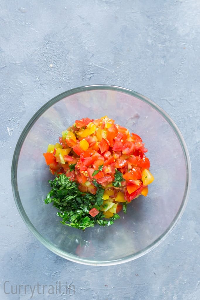 diced cherry tomatoes and fresh basil leaf in a glass bowl 