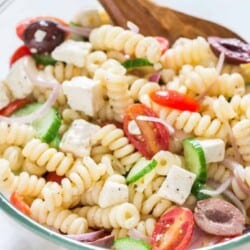 Greek pasta salad in a bowl with wooden spatula