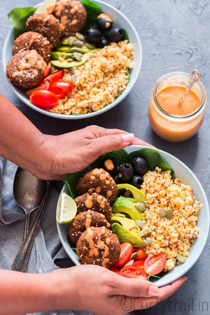 2 blue bowls having falafel, quinoa, vegetables all arranged for Mediterranean Vegan Buddha Bowl 
