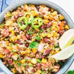 Mexican quinoa salad with lime wedges and jalapeno slices in a blue bowl