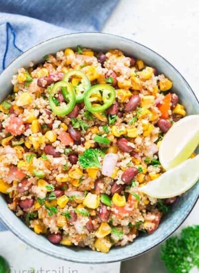 Mexican quinoa salad with lime wedges and jalapeno slices in a blue bowl