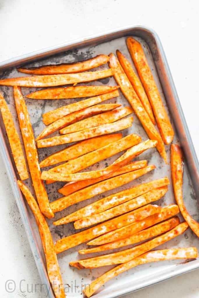 baked sweet potato fries arranged on baking tray