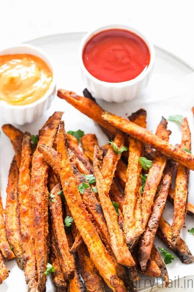 baked sweet potato fries on white plate with two dipping sauces on side
