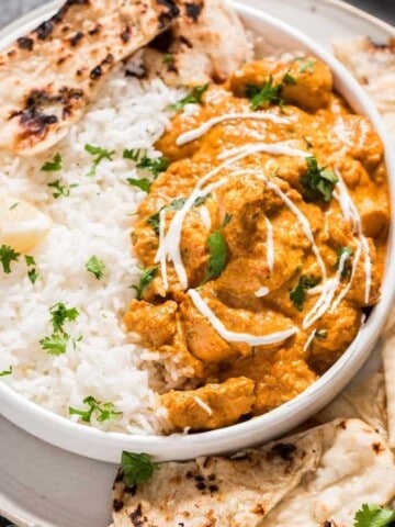 Instant pot butter chicken in white plate with rice and naan