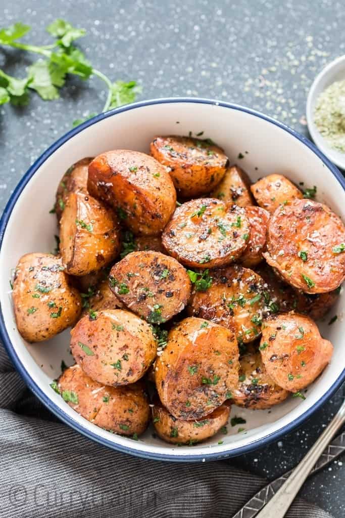 instant pot potatoes roasted with garlic butter and herbs served in white blue rim bowl