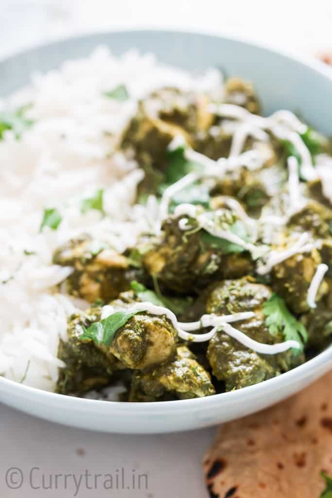 instant pot saag chicken with rice in a bowl and rotis on side