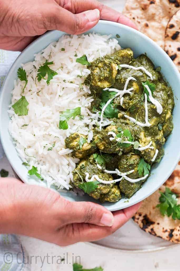 instant pot saag chicken with rice in a bowl and rotis on side