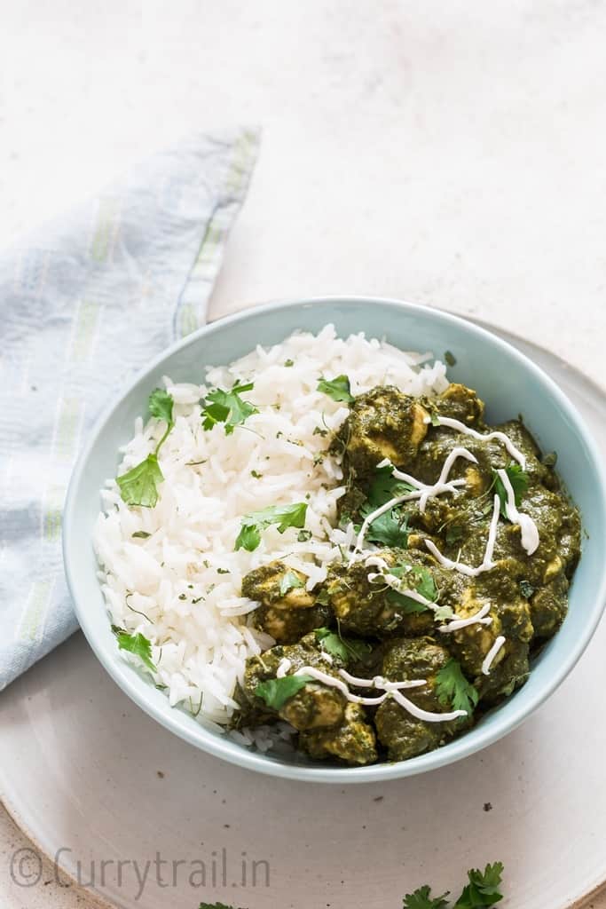 instant pot saag chicken with rice in a bowl and rotis on side