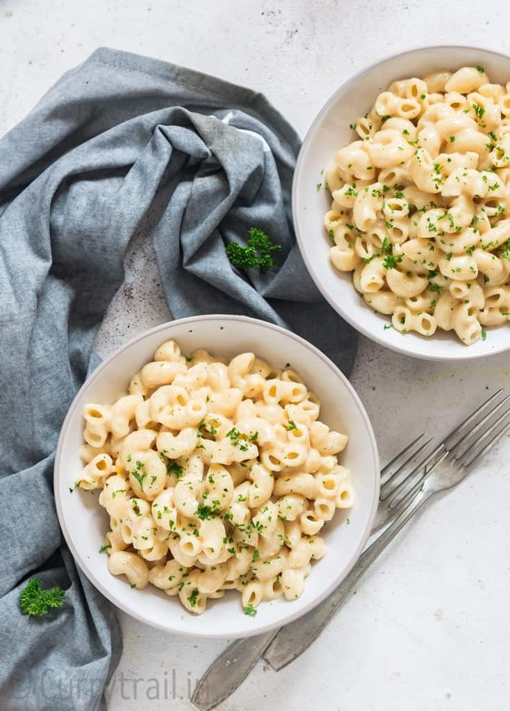 two white bowls of instant pot mac and cheese with fork and napkin on side