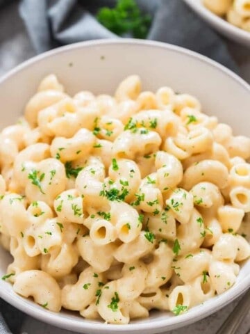 instant pot macaroni and cheese served in white bowls sprinkled with parsley