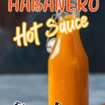 mango and habanero chilies hot sauce in glass jar with wooden spoon with text overlay