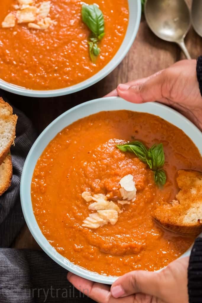 roasted tomato basil soup in 2 blue ceramic bowls with garlic bread on top