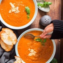 roasted tomato basil soup in 2 blue ceramic bowls with garlic bread on top