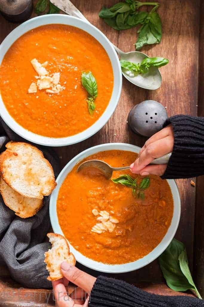 Tomato-Basil-Soup-20 roasted tomato basil soup served in two ceramic bowls with bread on side