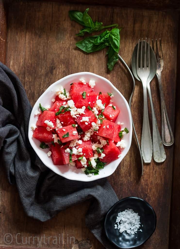 Watermelon feta salad with basil leaves served in white bowl