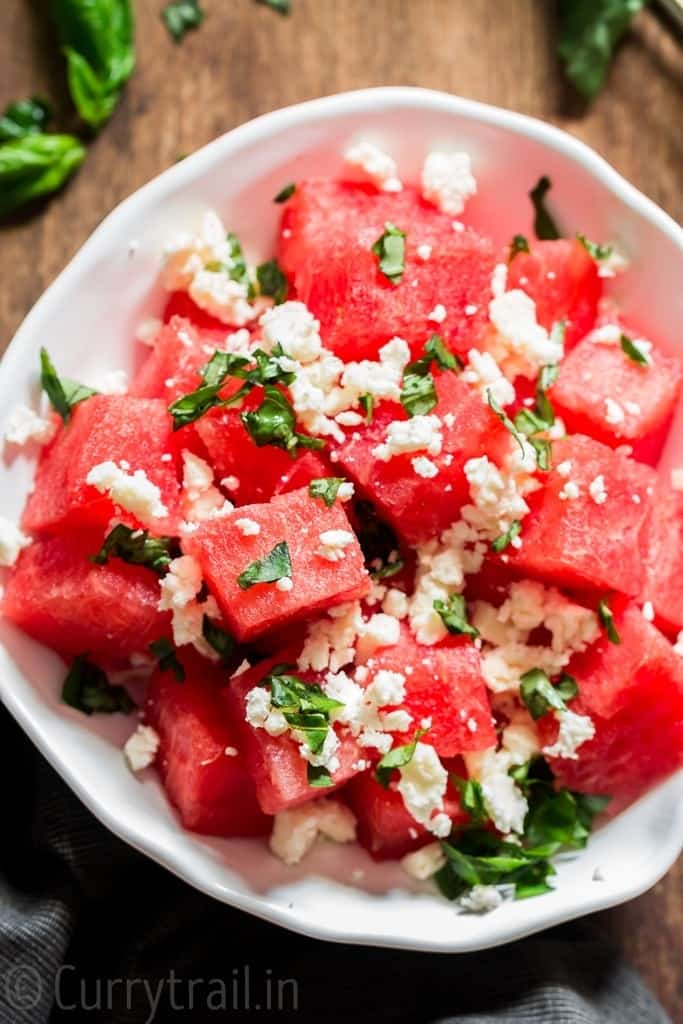 Watermelon feta salad with basil leaves served in white bowl