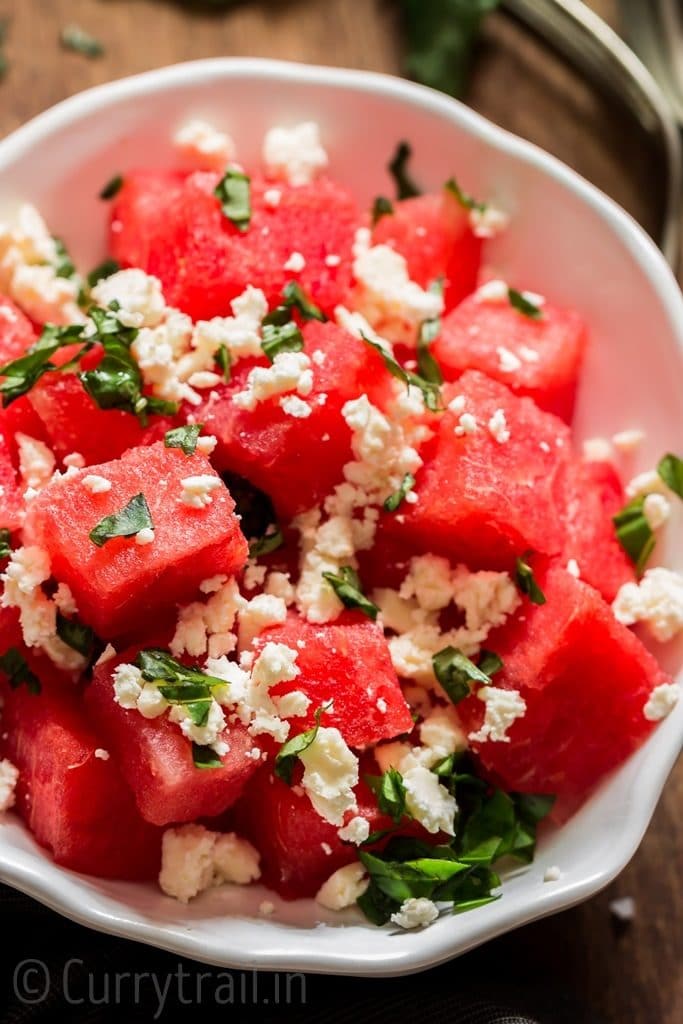 Watermelon feta salad with basil leaves served in white bowl
