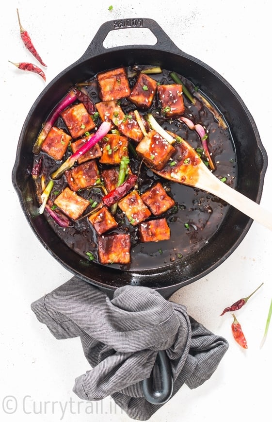 general tso's tofu cooked in cast iron pan with napkin tied to handle