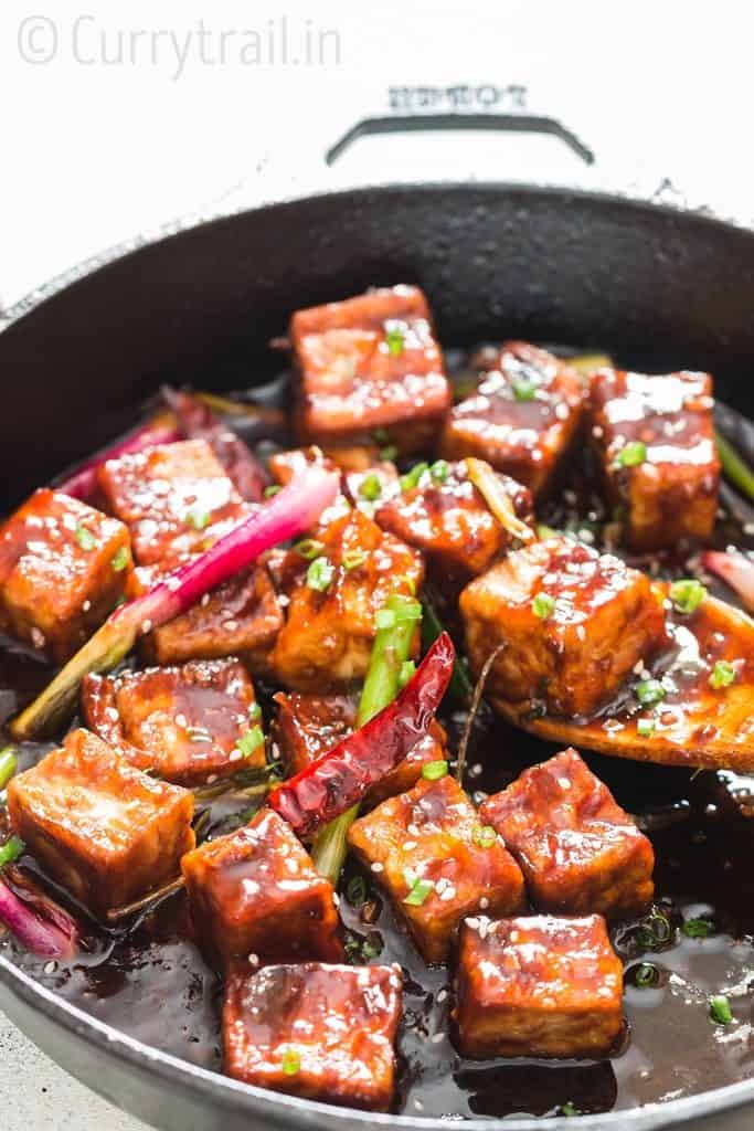 general tso's tofu cooked in cast iron pan with wooden spatula