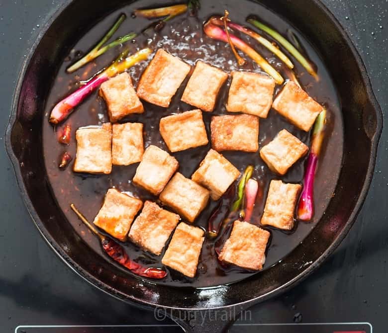 fried tofu cubes added to cast iron pan for general tso's tofu