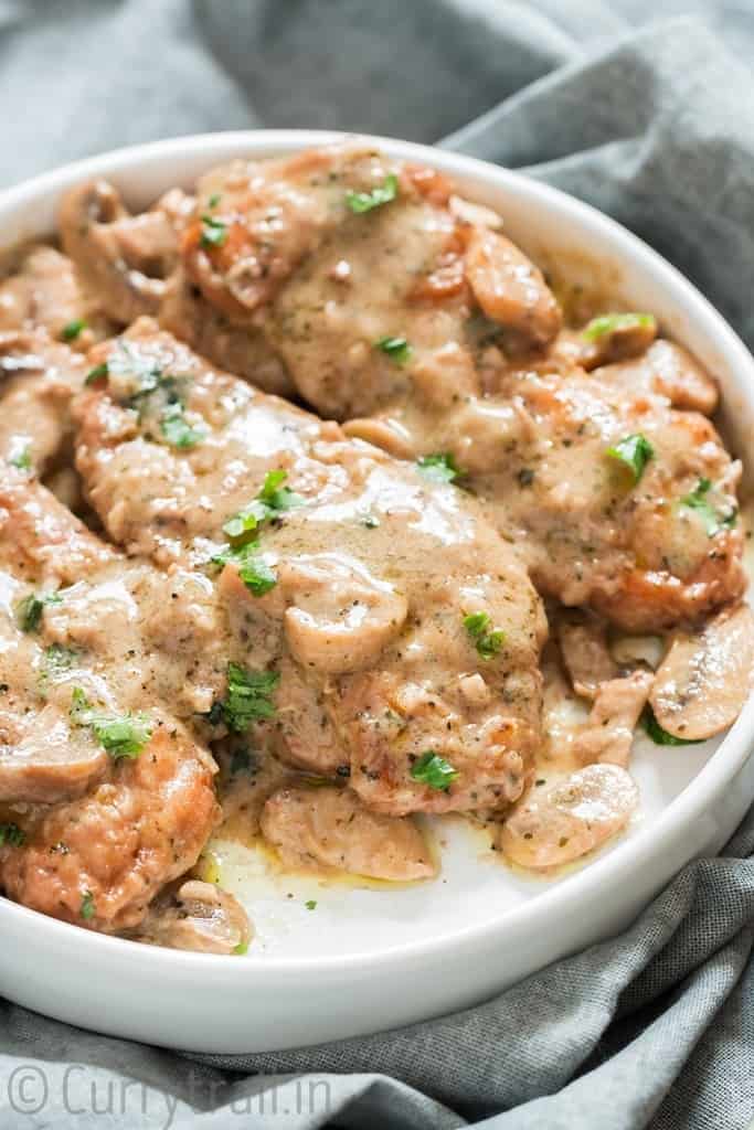 creamy sauce poured over chicken breasts on white plate for instant pot chicken marsala