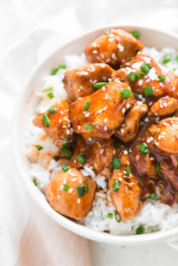 General Tso chicken over a bowl of rice in white bowl