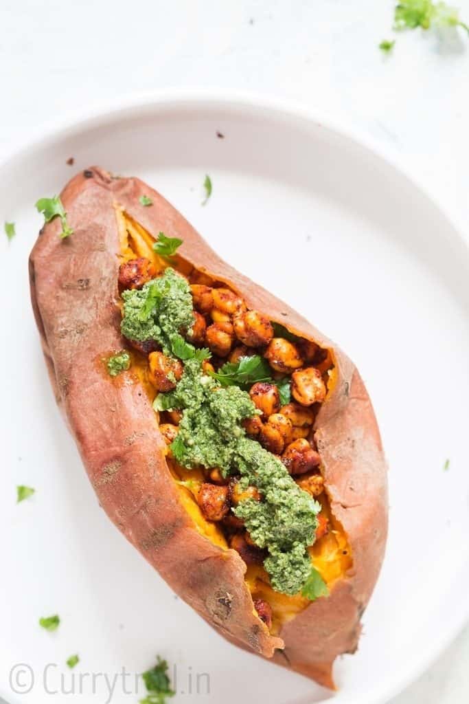 sweet potatoes stuffed with spicy chickpeas and pesto in the center placed on white plate