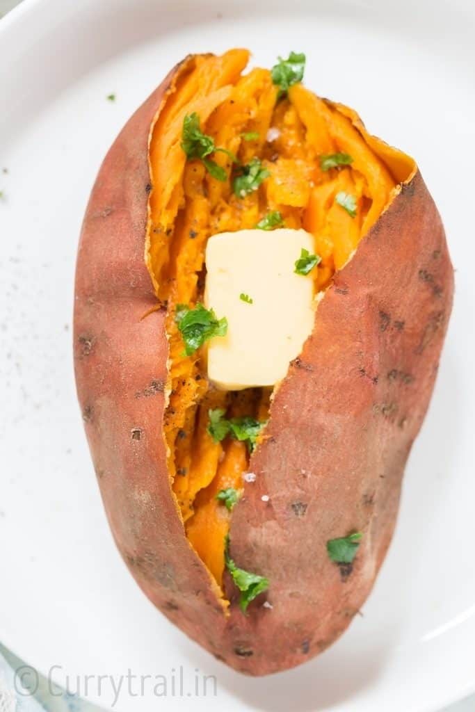 sweet potatoes on white plate mashed with cubes of butter sprinkled with cilantro