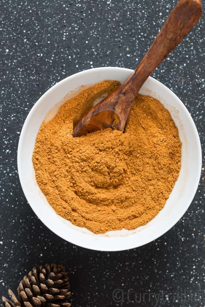 Mixing homemade pumpkin pie spice in white bowl with wooden handle