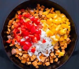 Red and yellow bell peppers added to pan