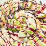 peanut butter and chocolate drizzled on apple nachos on white plate with text