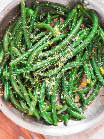 garlic sauteed green beans sprinkled with Parmesan and lemon zest Thanksgiving side dish cooked in skillet