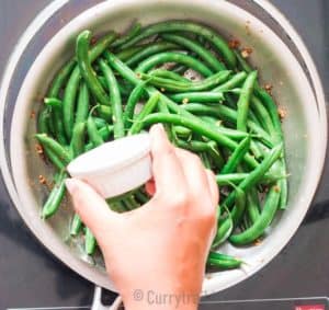 adding lemon juice to sauteed green beans in skillet