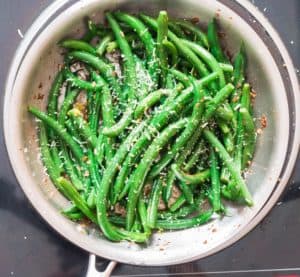 sauteed green beans garnished with lemon zest and Parmesan sauce
