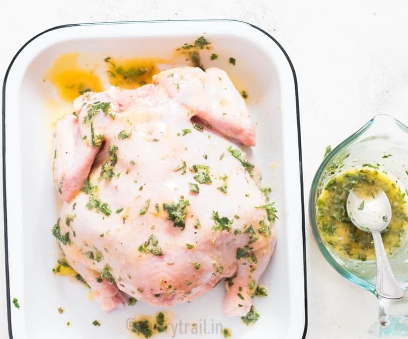 prepping pressure cooker whole chicken rubbed with buttery herb mix on a white tray.