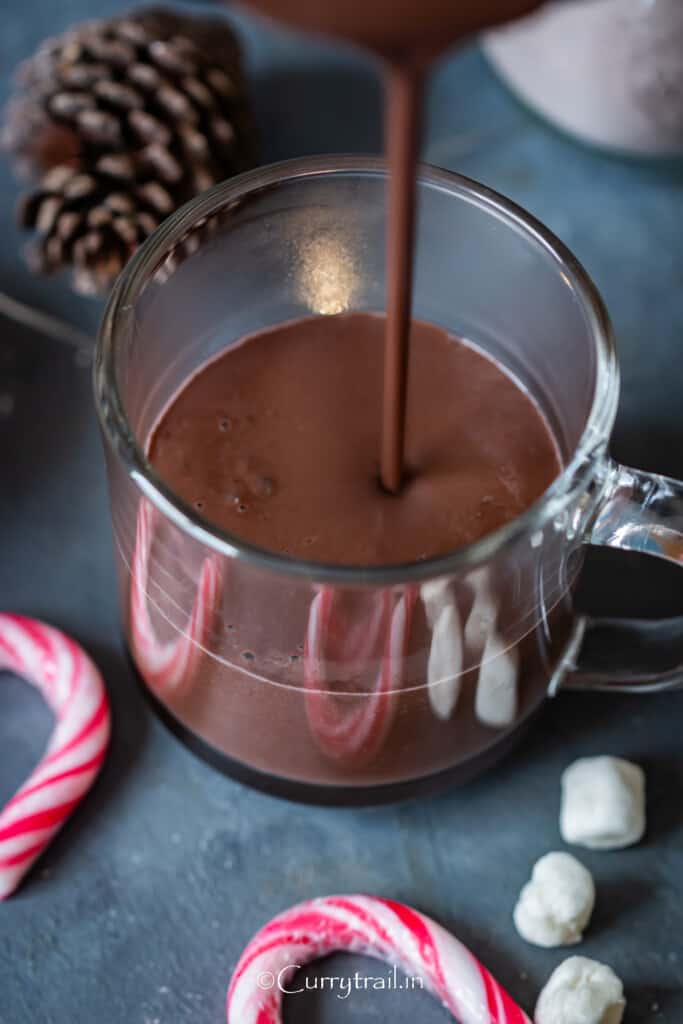 pouring hot cocoa into a glass jug.