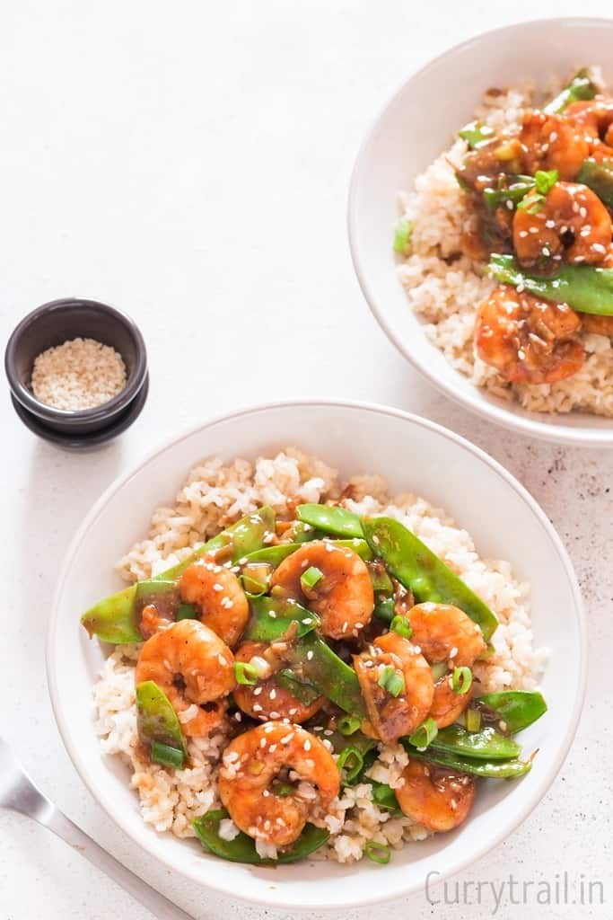 two bowls of rice with stir fried shrimp on top