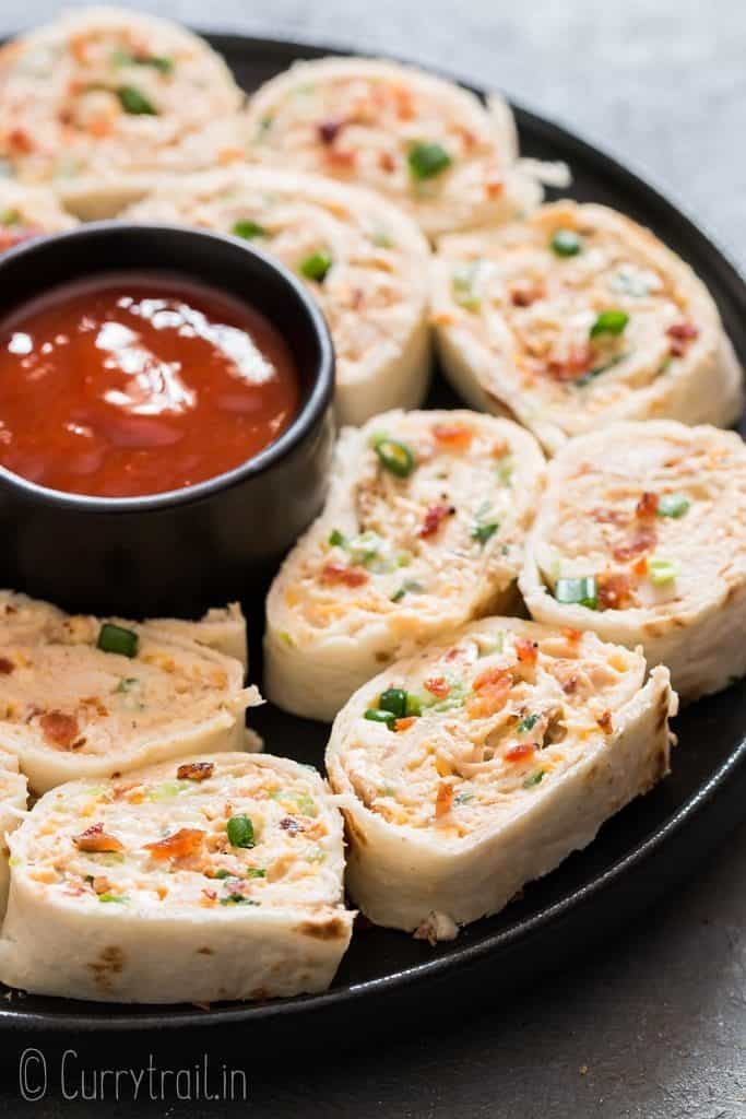 tortilla pinwheels with creamy chicken filling with spicy dipping sauce on a plate.