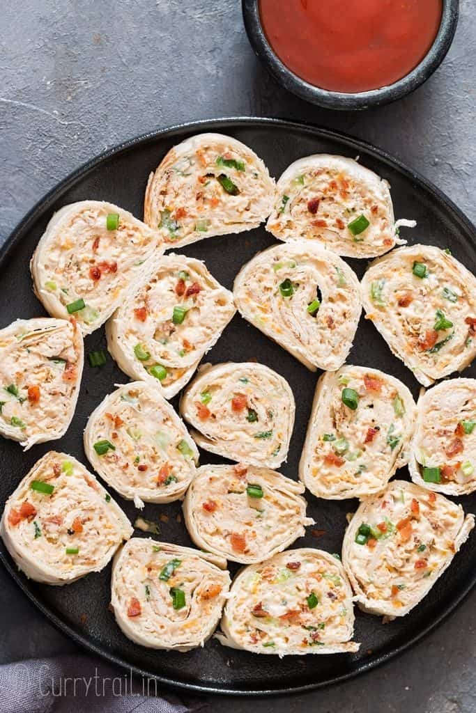 tortilla roll ups stuffed with shredded chicken enchilada with ketchup on the side.