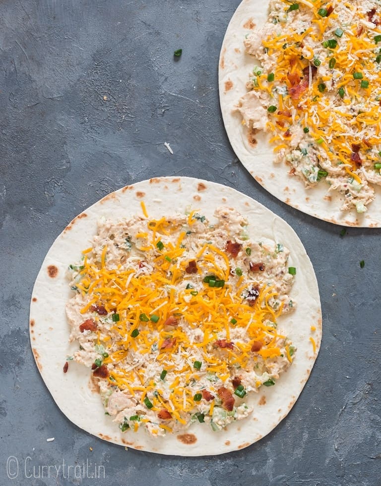 chicken tortilla roll-ups ready with cheese and green onions sprinkled on top ready to be rolled