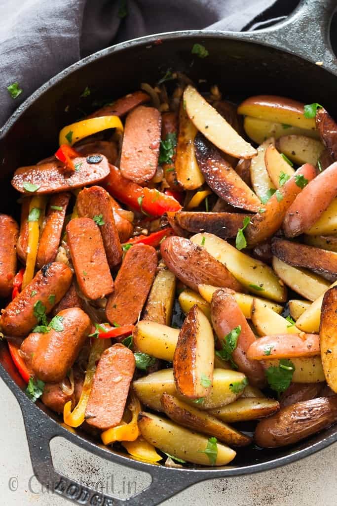 potatoes and sausages cooked in cast iron skillet with napkin on side